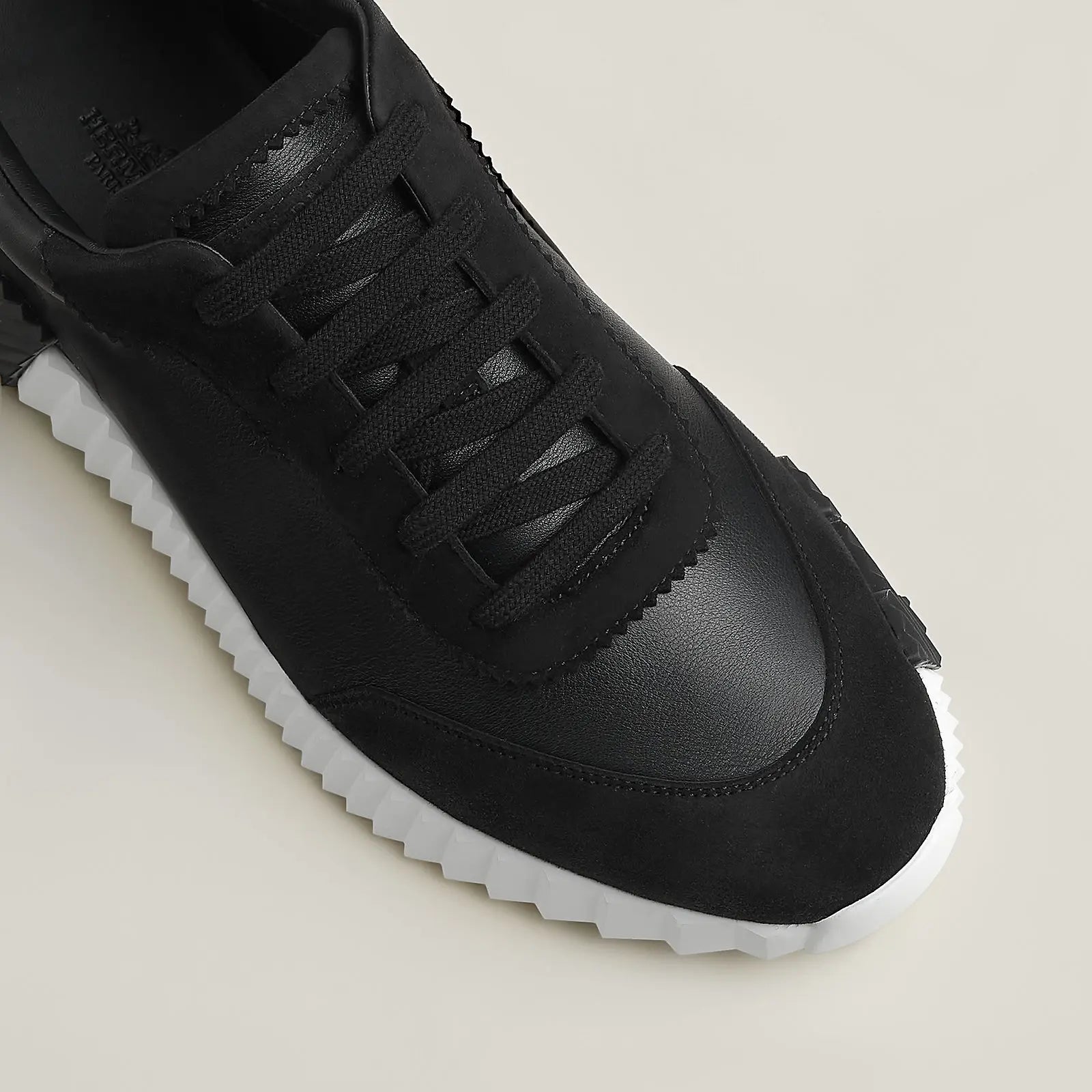 Hermes Bouncing Sneaker schwarz Herren – Detailansicht schwarzes H auf weißer gerippter Gummisohle