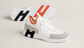 Weißer Hermes Slip-on-Sneaker aus Strickgewebe mit grauer Wildleder-Zehenkappe, orangefarbenem Bündchen und weißer Profilsohle – Seitenansicht