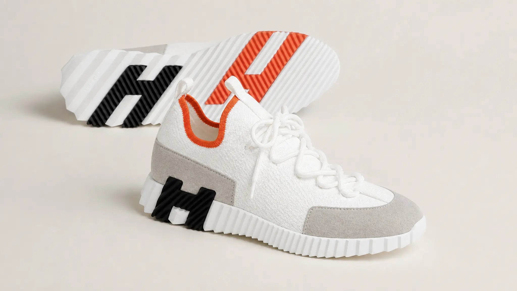 Weißer Hermes Slip-on-Sneaker aus Strickgewebe mit grauer Wildleder-Zehenkappe, orangefarbenem Bündchen und weißer Profilsohle – Seitenansicht