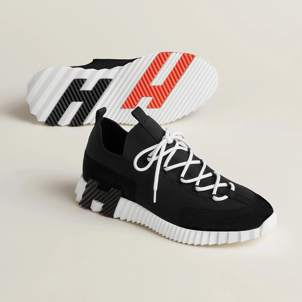 Schwarze Hermes Sneaker Herren mit weißer Profilsohle – Paar in Schrägansicht mit sichtbarem Sohlenmuster