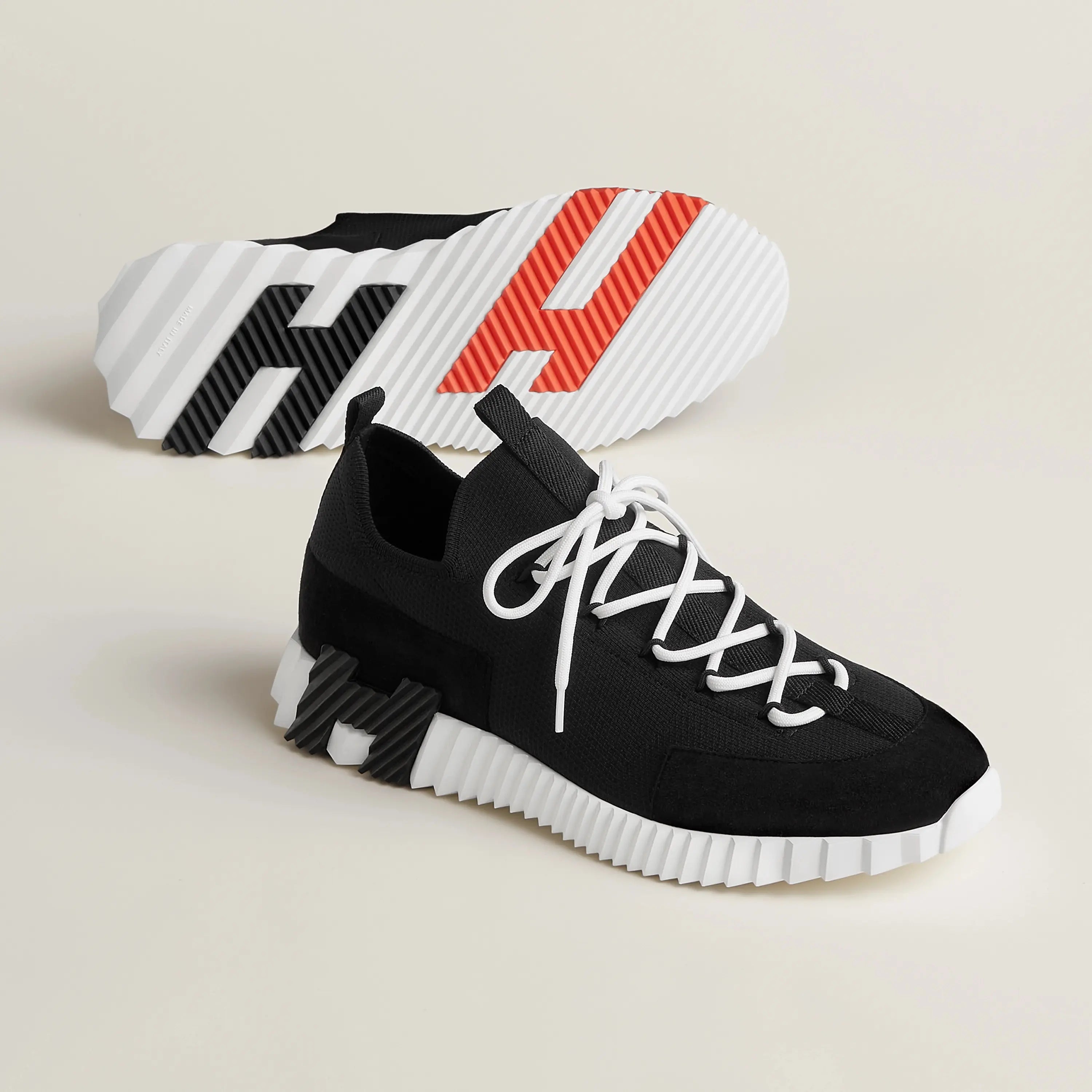 Schwarze Hermes Sneaker Herren mit weißer Profilsohle – Paar in Schrägansicht mit sichtbarem Sohlenmuster